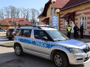 Umundurowani policjanci i oznakowany radiowóz przed Centrum Medycznym w Łańcucie.
