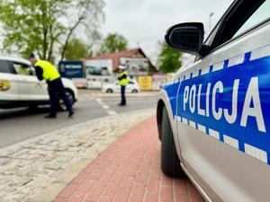 policjanci w tle, na pieszym planie radiowóz policyjny