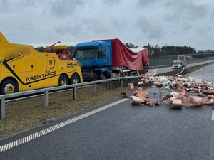 na jezdni stoja dwa pojazdy ciężarowe oraz porozrzucane metalowe elementy