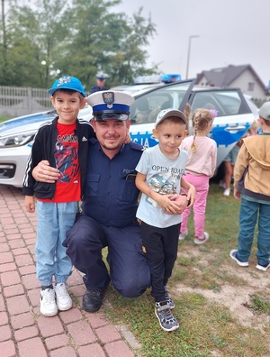 obok policjanta stoi dwóch chłopców