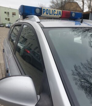 część policyjnego radiowozu z policyjna belka i napisem policja