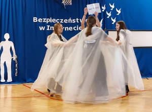 młodzież w białych pelerynach podczas spektaklu o cyberzagrożeniach