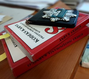 na kodeksach karnych leży policyjna odznaka