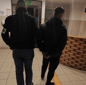 policjant kryminalny prowadzi mężczyznę w kajdankach