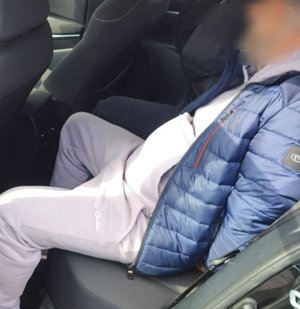 mężczyzna zatrzymany w kajdankach na tyle samochodu osobowego