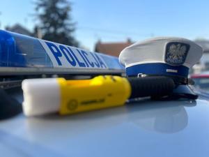 na dachu policyjnego radiowozu leży urządzenie do badania stanu trzeźwości iblow oraz policyjna czapka ruchu drogowego