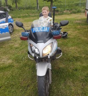 chłopiec siedzi na policyjnym motocyklu