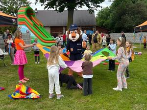 policyjna maskotka lew w otoczeniu dzieci podczas gier plenerowych