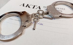 na zdjęciu teczka akt dochodzenia - śledztwa na której leżą kajdanki