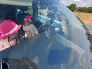 dziewczynki siedza w radiowozie policyjnym podczas imprezy plenerowej