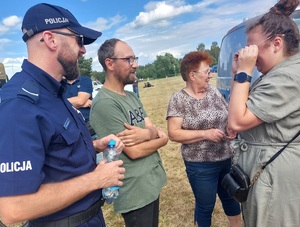 policjant rozmawia z uczestnikami imprezy plenerowej