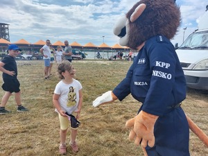 policyjna maskotka lew obok dziecka na imprezie plenerowej