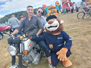 policyjna maskotka lew z uczestnikami imprezy plenerowej na motocyklu