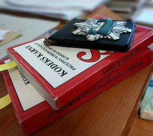 policyjna legitymacja leży na kodeksach karnych na biurku