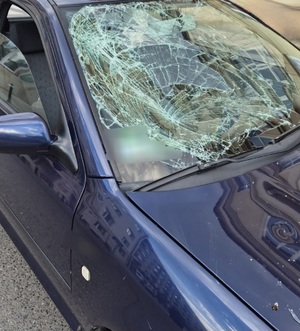 na zdjęciu uszkodzona szyba czołowa w samochodzie osobowym koloru granatowego