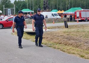 policjanci patrolujący teren imprezy plenerowej przy pomniku w kształcie orła