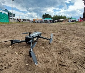 dron leżący na ziemi na placu imprezy plenerowej w tle namioty