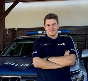 policjant stoi przy radiowozie