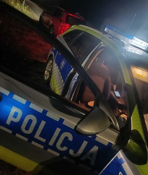 pora nocna policyjny radiowóz przy drodze a za nim pojazd osobowy przy którym stoi policjant