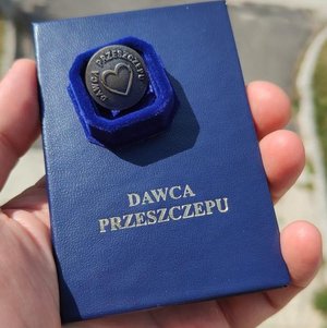 granatowa mała legitymacja z napisem dawca przeszczepu trzymana w dłoni zdjęcie autorstwa Krzysztof Luchowski