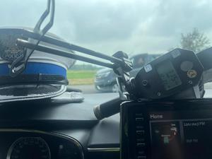 policyjny miernik prędkości leży na desce rozdzielczej samochodu osobowego obok leży policyjna czapka ruchu drogowego