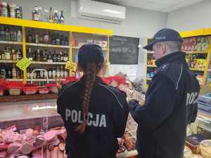 Policjantka  policjant stoją przed regałem sklepowym.