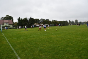 Na boisku piłkarze dwóch drużyn grają w piłę nożną.