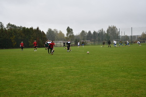 Na boisku piłkarze dwóch drużyn grają w piłę nożną.