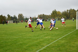 Na boisku piłkarze dwóch drużyn grają w piłę nożną.