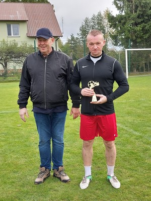 Zawodnik trzyma w rękach statuetkę najlepszego strzelca.