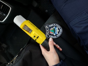 żółte urządzenie do badania stanu trzeźwości, w dłoni policjantki na tle emblematu KPP Nisko.