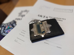 Na taczce akt leży policyjna legitymacja i emblemat KPP Nisko