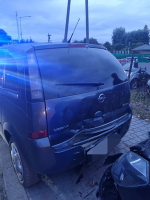 samochód opel stojący na chodniku, widoczna uszkodzona klapa bagażnika