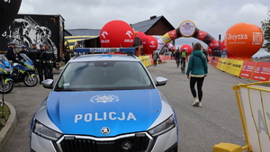 radiowóz policyjny, a w tle meta i start "Orlen Lang Team Race" i "Orlen Wyścig Narodów"
