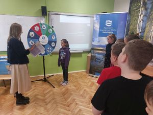 Przedstawicielka Wód Polskich wykonuje doświadczenia z dziećmi używając do nich wody