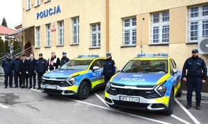 Kie Sportage  przed budynkiem komendy oraz osoby zaproszone na wspólny zdjęciu