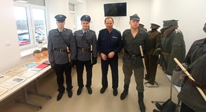 Wspólne zdjęcie policjanta z młodzieżą ubraną w mundury z okresu stanu wojennego