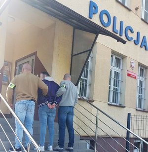 Osoba zatrzymana doprowadzana do komendy w asyście policjantów