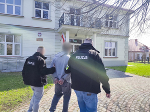 Policjanci prowadzą osobę zatrzymaną