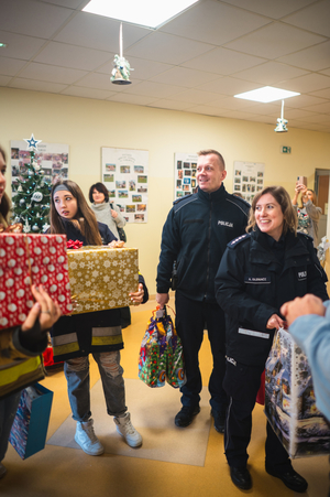 Policjanci wraz z wolontariuszami wnoszą paczki do budynku DPS w Sanoku