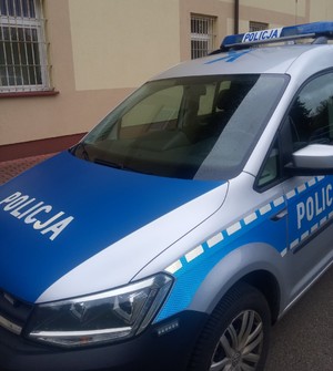 Oznakowany Radiowóz policyjny. W tle ściana budynku Komendy Powiatowej Policji w Sanoku.