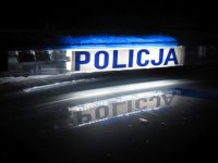 Belka z napisem POLICJA na dachu radiowozu. Zdjęcie zrobione w nocy, ciemne tło.