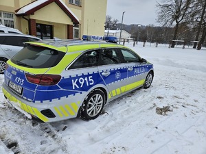 Oznakowany radiowóz zaparkowany na parkingu przy budynku.