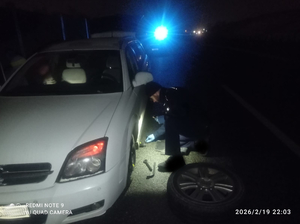 Policjant pomagający w wymianie koła w samochodzie. Właściciel pojazdy przesłał podziękowanie.