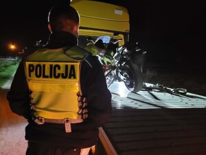 Policjant stojący przed lawetą, na której znajduje się motocykl
