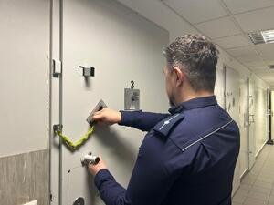 Policjant w pomieszczeniu dla osób zatrzymanych